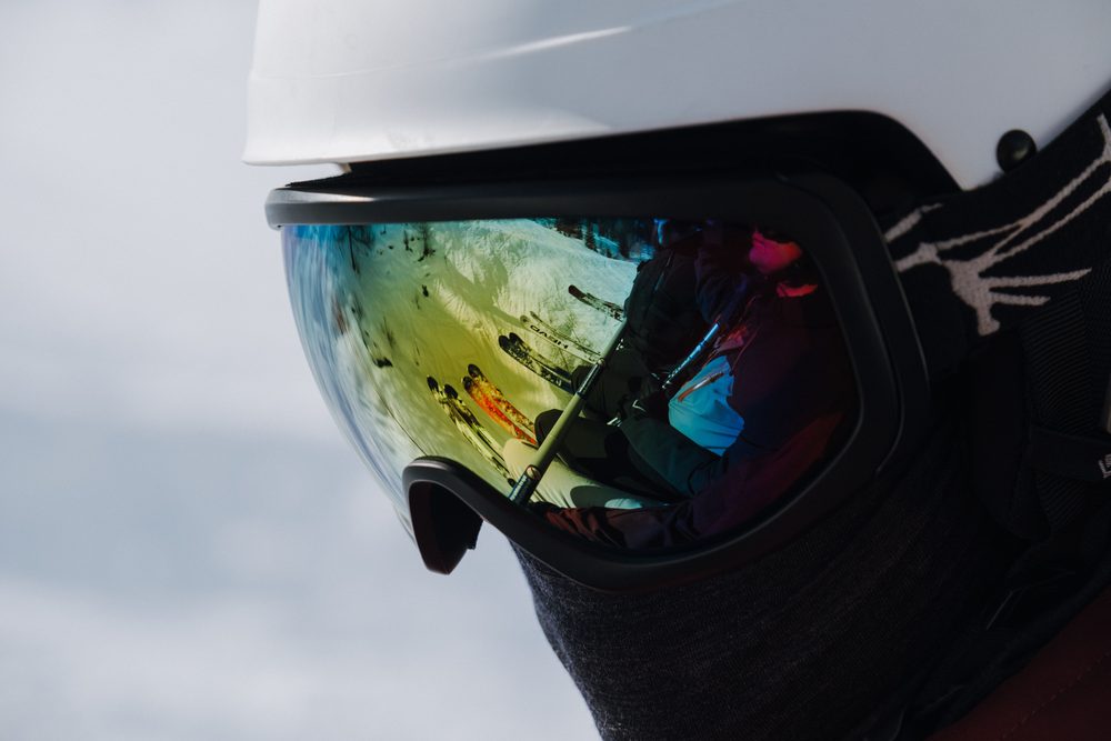 Close-up of ski goggles with a mirrored lens reflecting a snowy ski slope